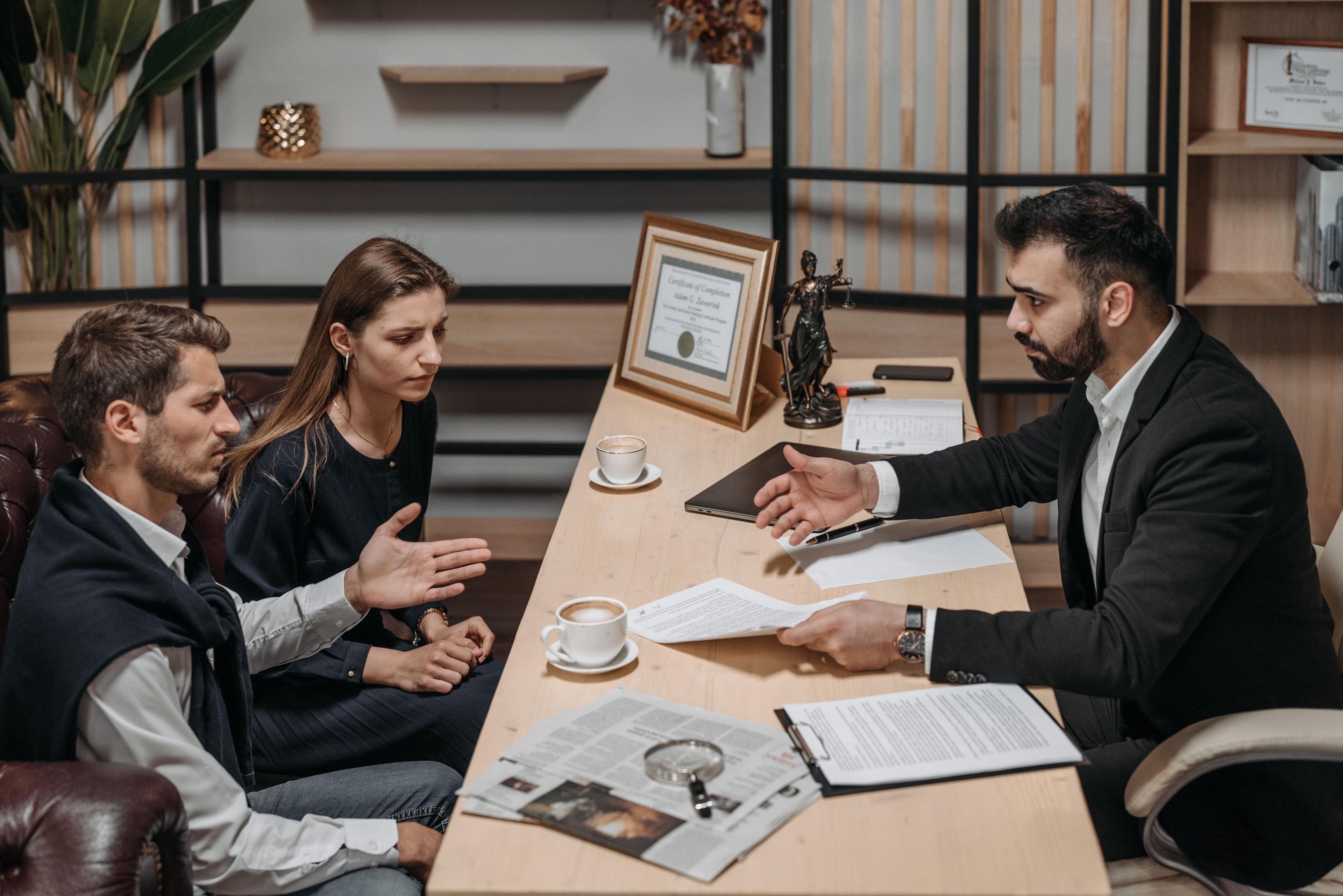 Legal professional consulting with clients over documents in a formal office setting